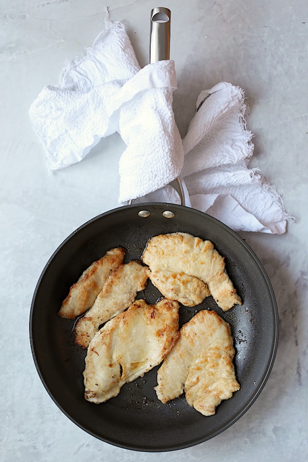 Overhead shot of turkey scallopini in large nonstick skillet that has been browned on both sides