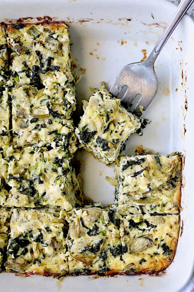 Photo of Spinach Artichoke Squares with a serving fork about to take a piece.