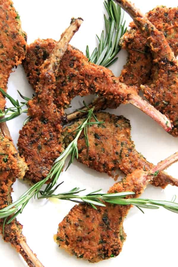 Photo of Parmesan and Herb-Crusted Lamb Chops on white background with rosemary sprigs.