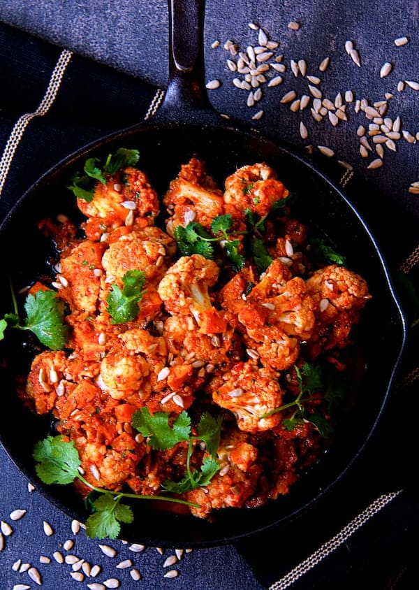 Photo of Cauliflower and Sweet Potatoes in Roasted Red Pepper Mole in cast iron skillet.