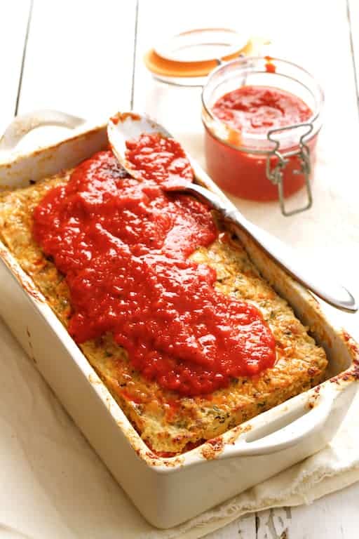 Photo of Layered Turkey Meatloaf with Roasted Red Pepper Sauce on white background with sauce partially spread over the top.