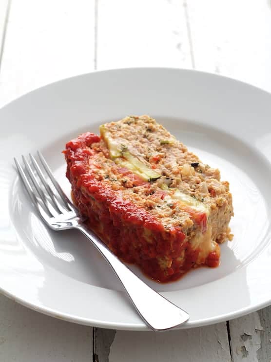 Photo of one slice of Layered Turkey Meatloaf with Roasted Red Pepper Sauce on white plate with fork.