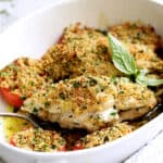Pesto and Goat Cheese-Stuffed Chicken with Roma Tomatoes - Finished dish being served with serving fork from white baking dish