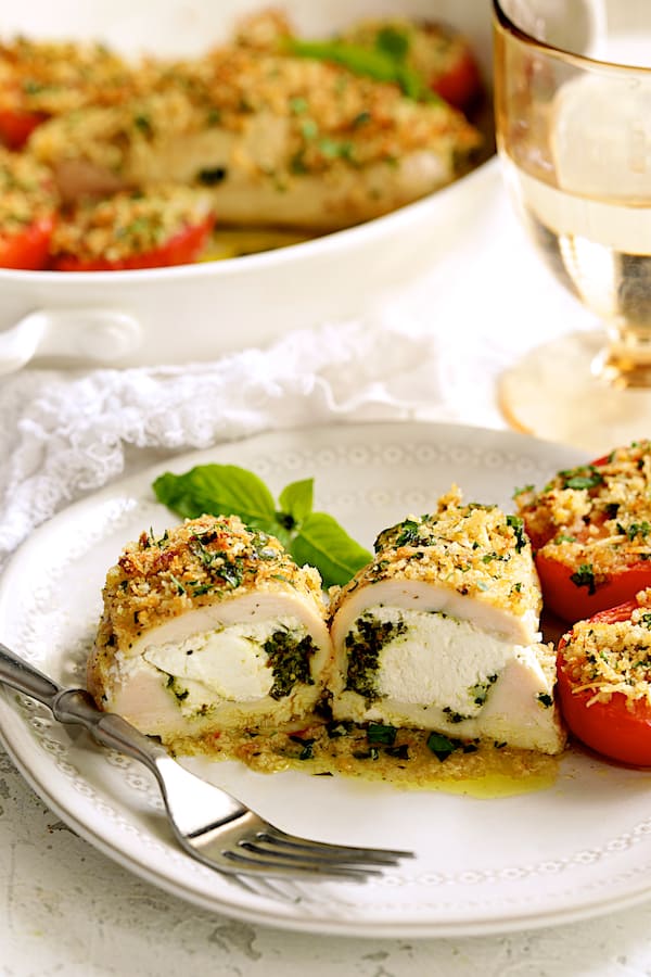 Close-up photo of Pesto and Goat Cheese-Stuffed Chicken with Roma Tomatoes cut in half to reveal pesto and goat cheese filling.