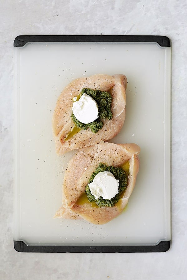 Photo of butterflied chicken breasts with pesto and goat cheese placed in the center.