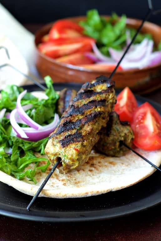 Photo of Grilled Turkish Ground Lamb Kebabs on pita bread with tomatoes, lettuce and red onion.