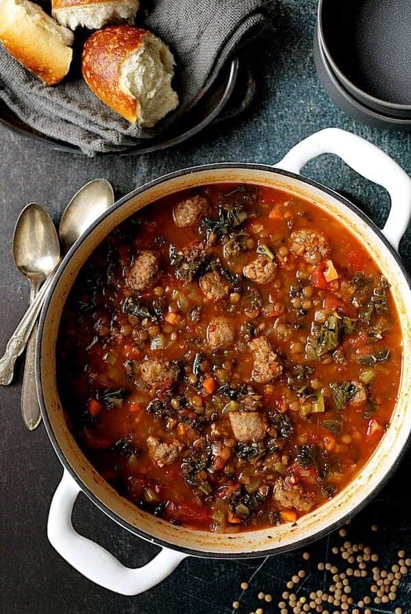 Sausage and Lentil Soup with Kale in white Dutch oven.