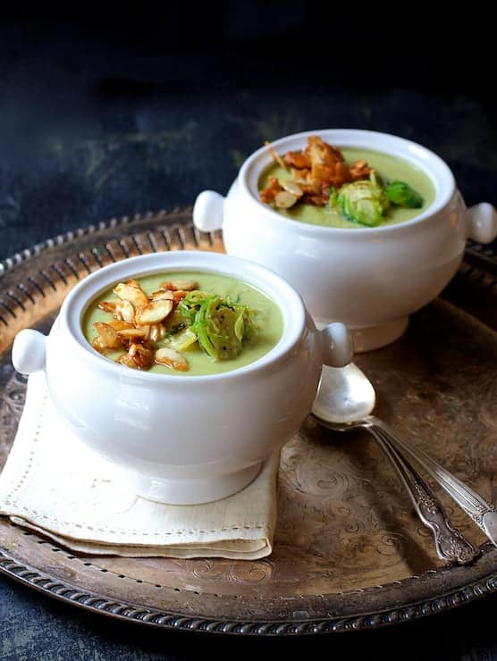 Photo of two bowls of Cream of Brussels Sprouts Soup with Butter Roasted Almonds on serving platter.