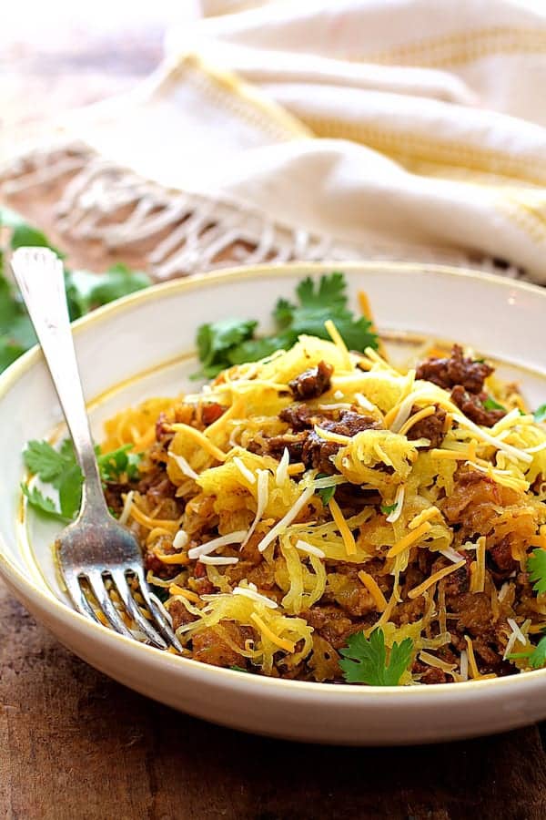 Photo of Spaghetti Squash Fideos in white bowl with yellow striped towel in the background.