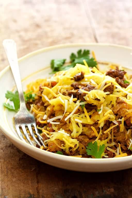 Close-up photo of Spaghetti Squash Fideos in white bowl garnished with cilantro sprigs.