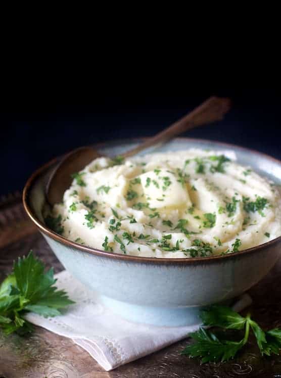 Celery Root Puree in serving bowl garnished with a pat of butter and chopped fresh parsley.