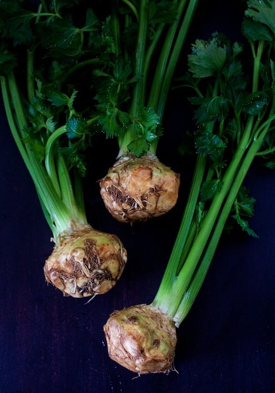 Photo of three bulbs of celery root also known as celeriac with tops attached.