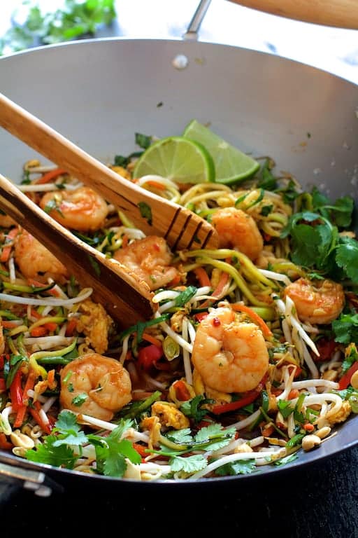 Photo of Shrimp Pad Thai with Zucchini Noodles in wok being stirred with wood tongs.