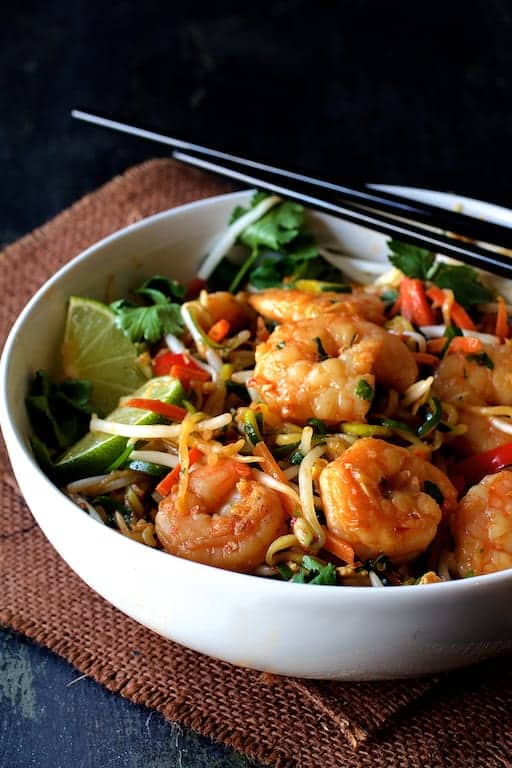 Photo of Shrimp Pad Thai with Zucchini Noodles in white bowl on brown burlap with black chopsticks.