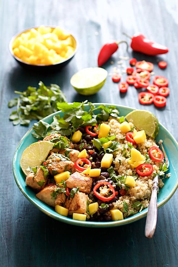 Photo of Cuban Chicken and Black Bean Quinoa Bowls with garnishes in the background.