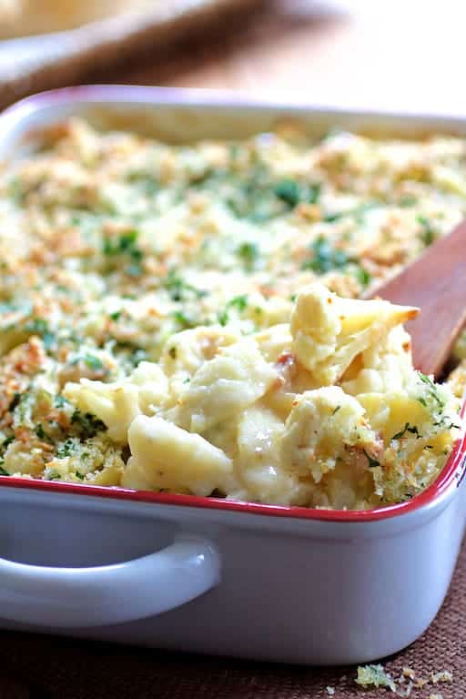 Close-up photo of Baked Orecchiette with Cauliflower, Bacon and Taleggio with wooden spoon removing some of the dish.