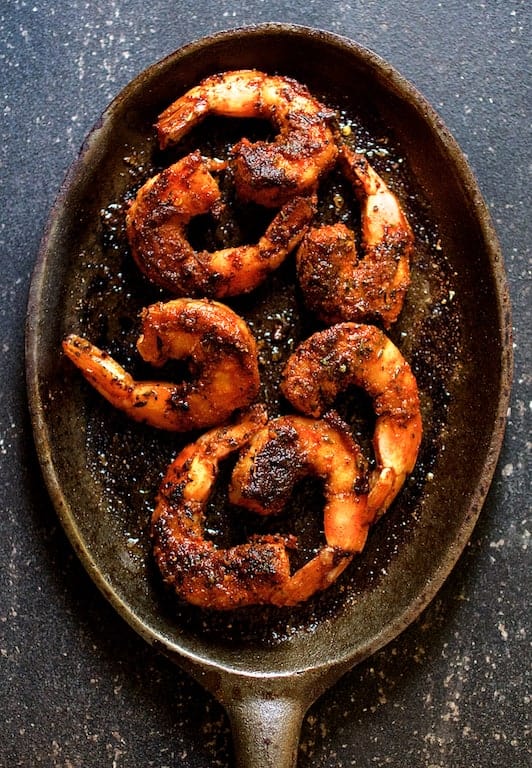 Photo of seven Blackened Shrimp on cast iron pan.