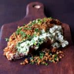 Green Chile Goat Cheese Stuffed Chicken Breasts with Spicy Cornmeal Pecan Crust on wood cutting board.