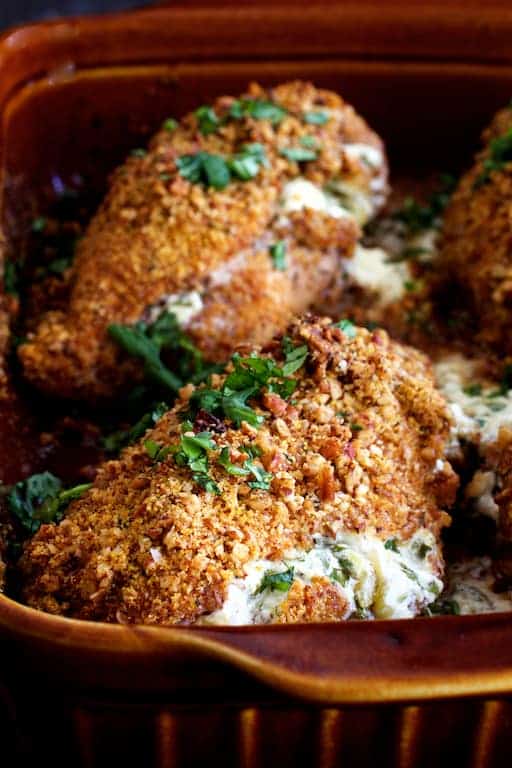 Photo of Green Chile Goat Cheese Stuffed Chicken Breasts with Spicy Cornmeal Pecan Crust in clay baking dish.