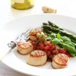 Seared Sea Scallops with Tomato, Red Onion and Balsamic Salsa with roasted asparagus on white plate.