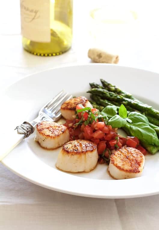 Seared Sea Scallops with Tomato, Red Onion and Balsamic Salsa with roasted asparagus on white plate.
