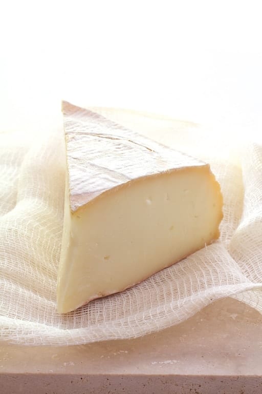 Photo of a wedge of Tallegio cheese on white cheesecloth.