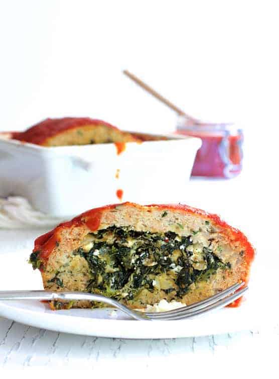 Slice of Spinach Feta Stuffed Turkey Meat Loaf on white plate showing the filling.