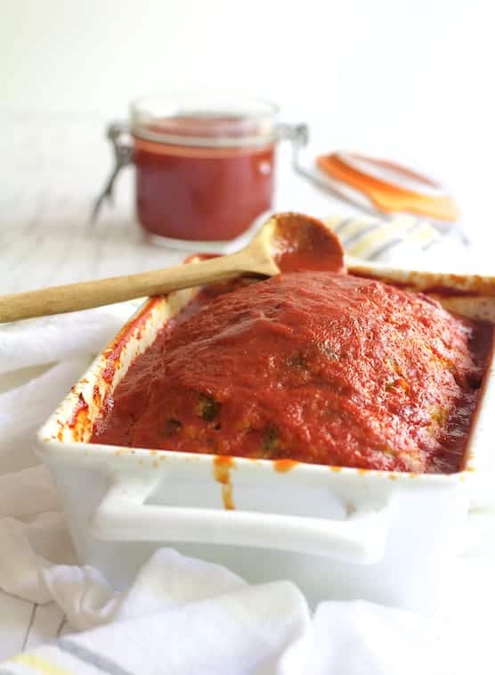 Photo of Spinach Feta Stuffed Turkey Meatloaf in white loaf pan on white background.