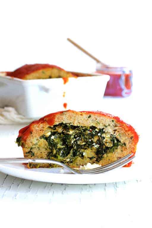 Close-up photo of a slice of Spinach Feta Stuffed Turkey Meatloaf on white plate revealing the inside.