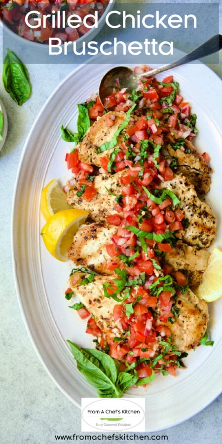 Pinterest graphic for Chicken Bruschetta showing it on an oval white platter garnished with lemon wedges and fresh basil.