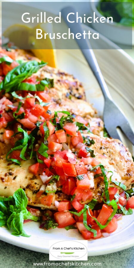 Pinterest graphic for Chicken Bruschetta showing it on an oval white platter garnished with lemon wedges and fresh basil.