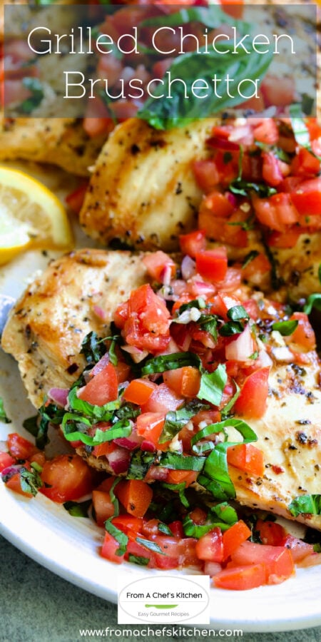 Pinterest graphic for Chicken Bruschetta showing it on an oval white platter garnished with lemon wedges and fresh basil.