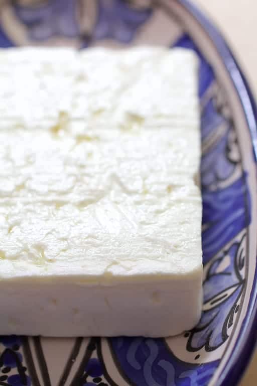 Photo of a block of feta cheese on blue decorative plate.