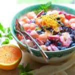 Summer Fruit Salad with Orange Yogurt Vanilla Dressing in green decorative bowl garnished with orange zest.