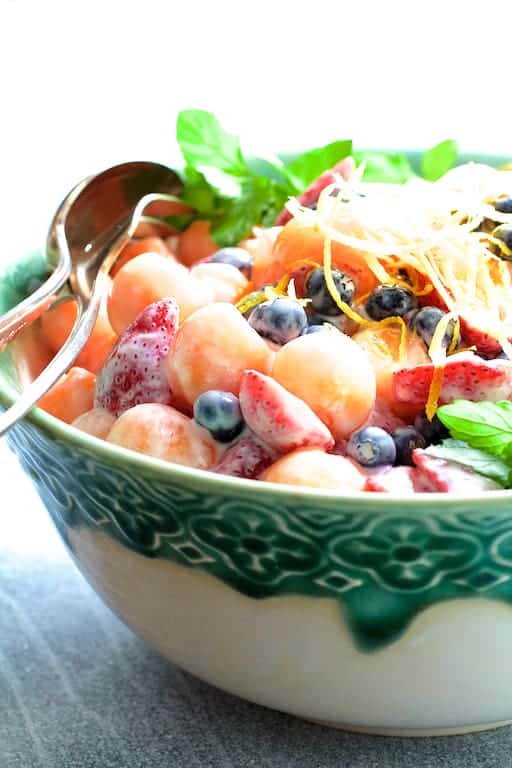 Close-up photo of Summer Fruit Salad with Orange Yogurt Vanilla Dressing in green and white bowl.