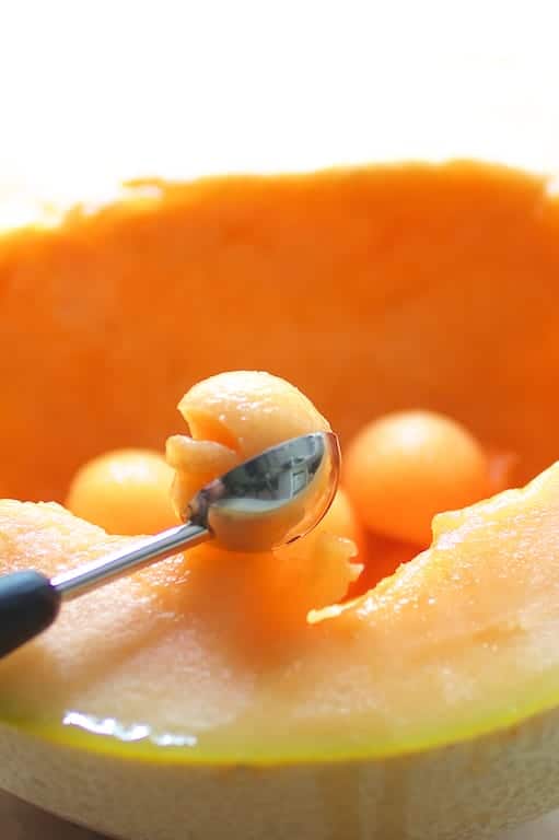 Photo of a melon being made into balls with melon baller.