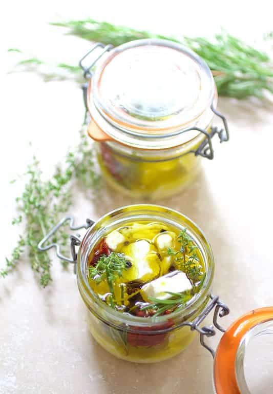 Photo of marinated feta cheese in glass jars.
