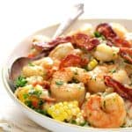 Shrimp and Corn Risotto with Bacon in white bowl with serving spoon.