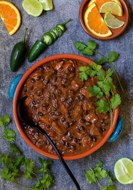 Photo of Feijoada (Brazilian Beef Stew) in serving bowl garnished with cilantro, jalapeno slices and orange and lime slices.