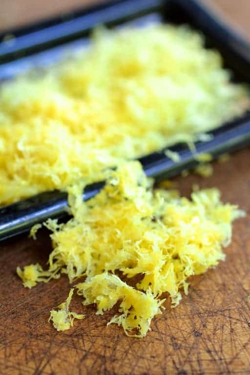 Photo of lemon zest on wooden surface with grater.