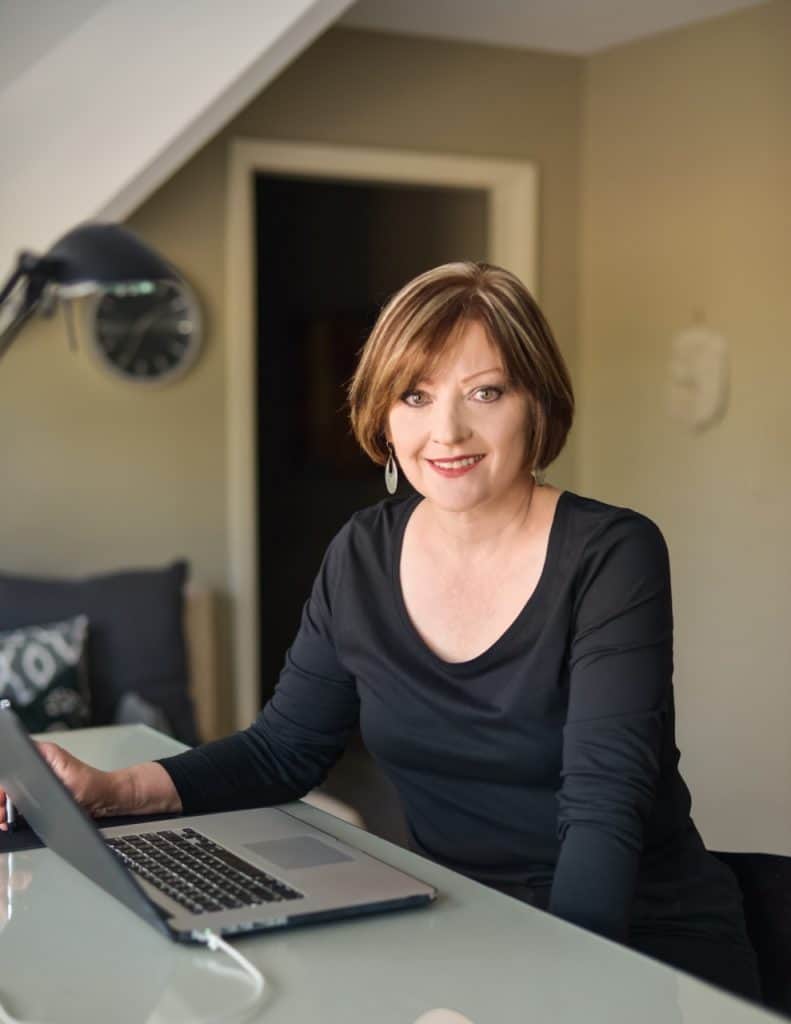 Photo of Carol Borchardt at her desk in front of computer.