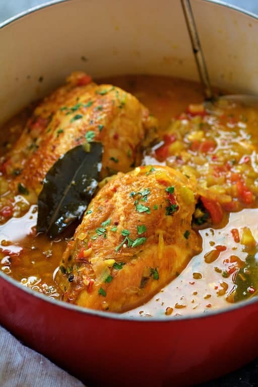 Close-up photo of Chicken Bouillabaisse in red Dutch oven with soup ladle.