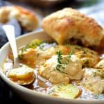 Chicken Bouillabaisse in white bowl with bread.