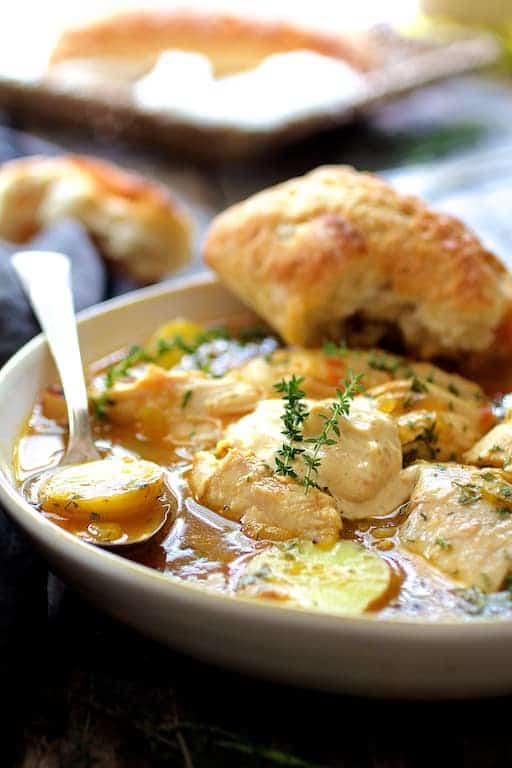 Chicken Bouillabaisse in white bowl with bread.