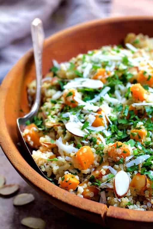 Close-up photo of Lemony Quinoa with Butternut Squash Almonds and Parmesan Cheese - Straight-on close-up shot in wooden bowl with serving spoon.