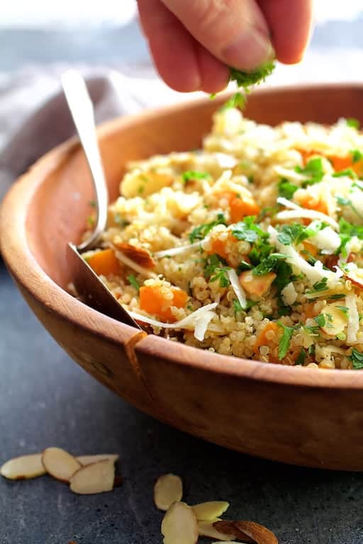 Photo of parsley being sprinkled on Lemony Quinoa with Butternut Squash, Almonds and Parmesan Cheese.