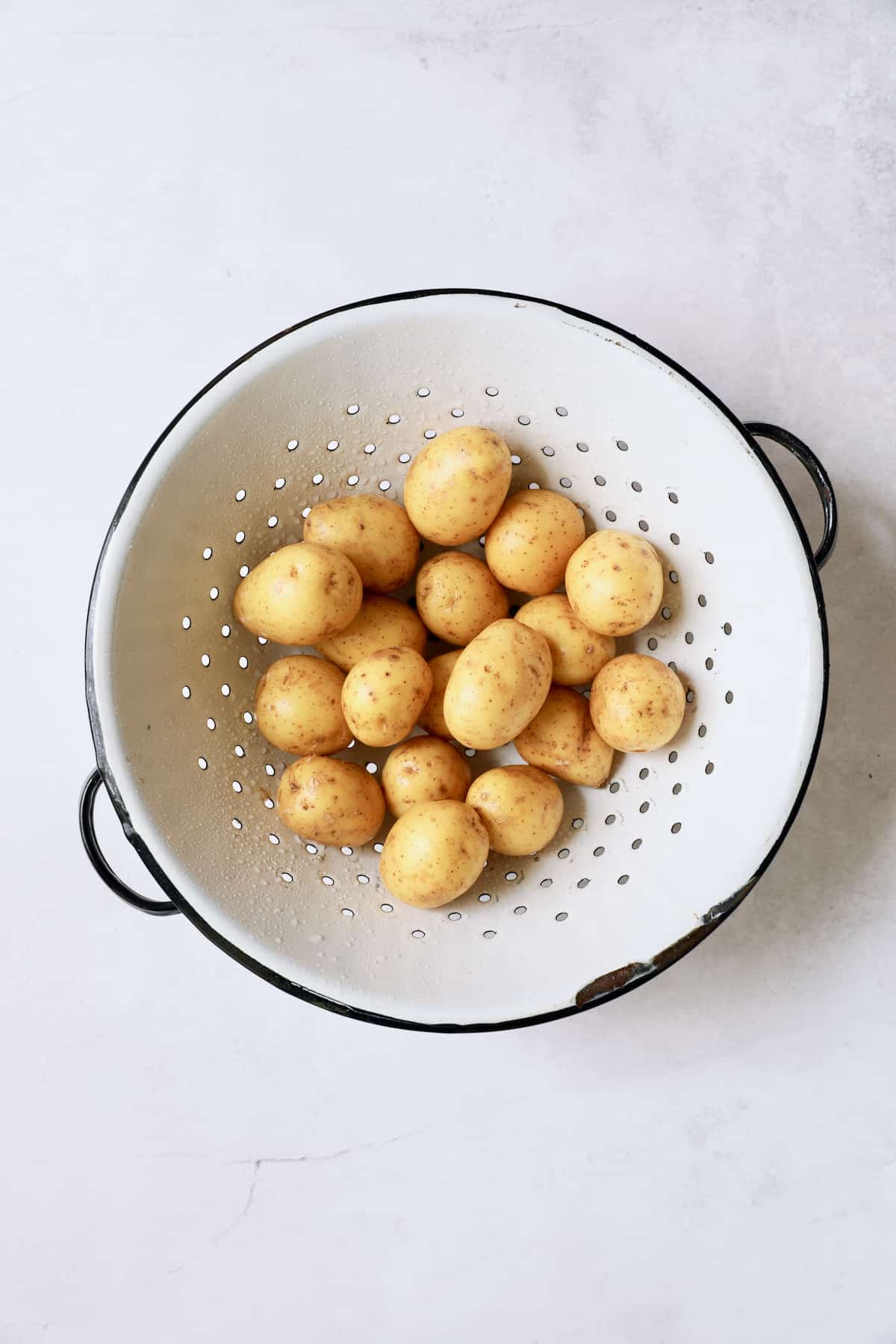 Photo of baby Yukon Gold potatoes in old white colander.