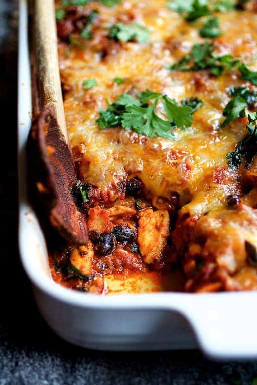 Mexican Chicken Tortilla Casserole in white baking dish with some removed.
