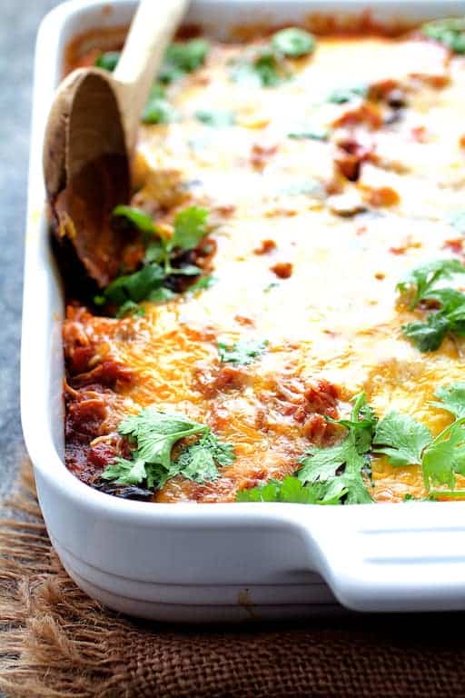 Photo of Chicken Poblano and Black Bean Tortilla Casserole in white ceramic baking dish before being served.