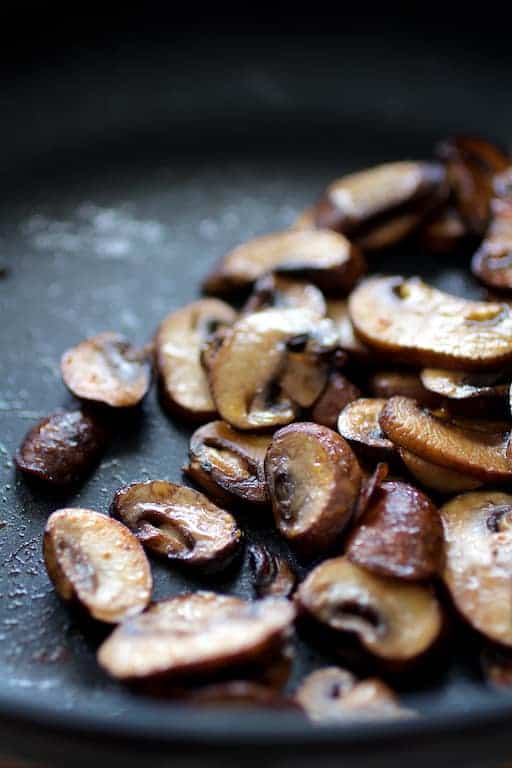 Photo of baby Portobello mushrooms being sauteed in nonstick skillet.